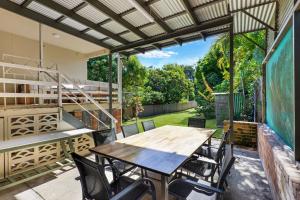 - patio z drewnianym stołem i krzesłami w obiekcie Place au Soleil w mieście Coffs Harbour