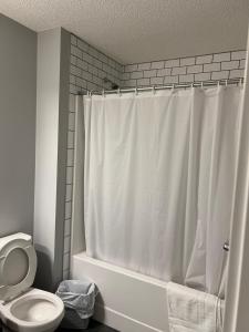 ein Badezimmer mit einem weißen Duschvorhang und einem WC in der Unterkunft Entire House in Calgary