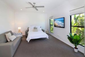 a white living room with a couch and a bed at Alex Heads Beach Haven in Alexandra Headland