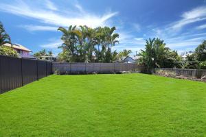 un gran patio con una valla y césped verde en Alex Heads Beach Haven, en Alexandra Headland