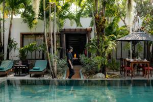 un homme debout en face d'un complexe avec une piscine dans l'établissement Bunwin Siem Reap, à Siem Reap