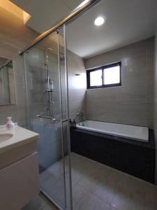 a bathroom with a shower and a tub and a sink at Caiteng B&B in Zhongli