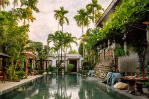 a woman stands in front of a pool in a house with palm trees at Bunwin Siem Reap in Siem Reap