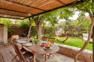 une table et des chaises en bois sous une pergola en bois dans l'établissement Very warm villa "Acacia" with beautiful garden - 46 people, à Calvi