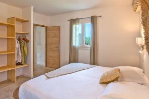 a bedroom with a white bed and a window at Villa Albizzia with terrace and garden 68 people in Calvi
