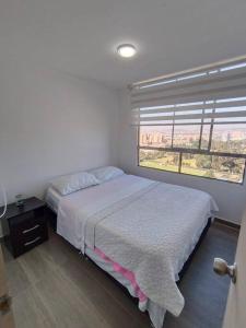 a bedroom with a bed and a large window at Apartamento - Cardio Infantil CTIC in Bogotá