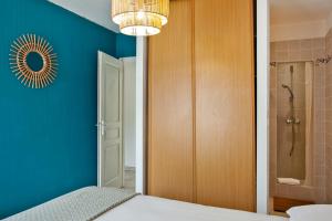 a bedroom with a blue wall and a chandelier at Apartment "Jasmin" 3 bedrooms with large terrace 68 people in Calvi