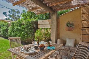 a wooden table and chairs under a pergola at Small quiet house Dracena with its pretty garden - 2 people in Calvi