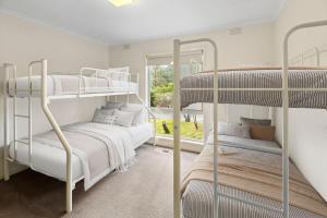 two bunk beds in a room with a window at Basecamp Sawmill in Mount Buller