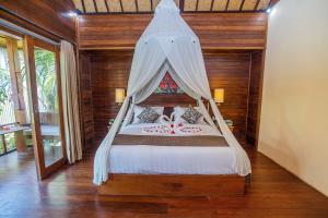 een slaapkamer met een hemelbed bij D'Muncuk Huts Lembongan in Nusa Lembongan