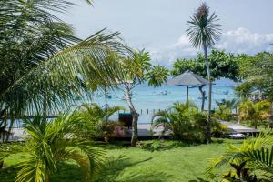 een uitzicht op de oceaan vanuit een resort met palmbomen bij D'Muncuk Huts Lembongan in Nusa Lembongan