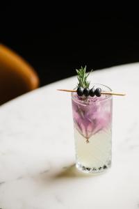 a glass of water with blackberries and a plant in it at Hilton Brisbane in Brisbane