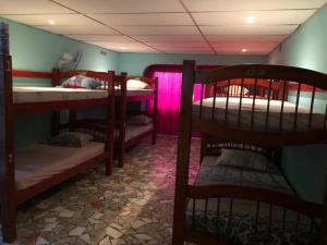 a room with several bunk beds with pink lighting at Hostal Portobelo in Portobelo