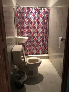 a bathroom with a toilet and a shower curtain at Hostal Portobelo in Portobelo