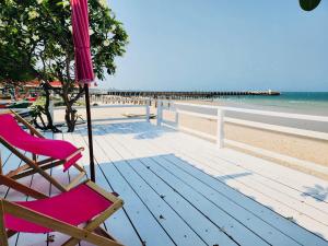 a wooden deck with a chair and an umbrella on the beach at Karoon hut in Hua Hin