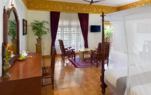 a bedroom with a bed and a table and chairs at Bethsaida Hermitage in Kovalam