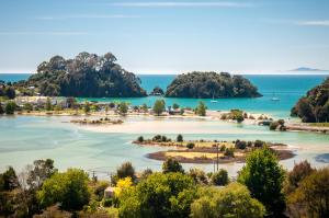 an island in the ocean with trees in the foreground at Yurt retreat in Pangatotara