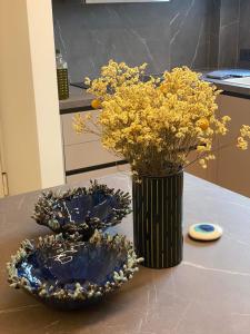 a vase with yellow flowers and two plates on a table at Sapfo Luxury Apartment in Athens in Athens