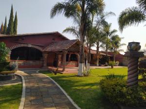 a house with a palm tree and a pathway at Hotel Villas San Miguel in Pátzcuaro