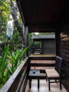 a wooden porch with a chair and a bench at Greenland Cottage's Arambol in Arambol