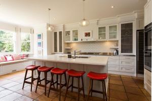 una cocina con armarios blancos y taburetes rojos en Victorian Masterpiece, en Sídney