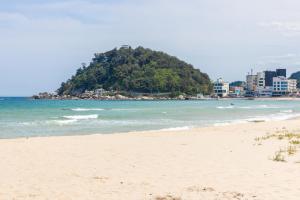 a sandy beach with an island in the ocean at Blue12 Yangyang Neos in Yangyang