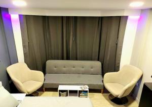 Habitación con 2 sillas, 1 cama y 1 mesa en Executive Suites Minutes From the Airport, en Bogotá