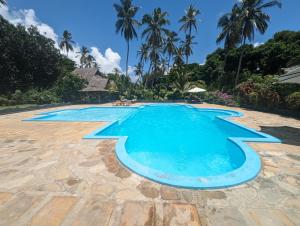 a pool at a resort with palm trees in the background at Kivulini Lodge in Utende