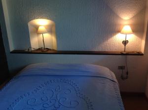 a bedroom with a bed with two lights on the wall at Condominio Colmet in La Thuile