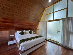 sypialnia z dużym łóżkiem i dużym oknem w obiekcie Suvarna Eco Village w mieście Madikeri