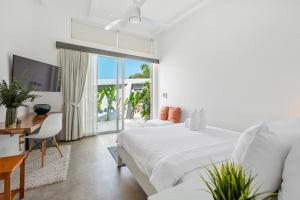 a white bedroom with a bed and a table and a desk at Villa Playa Samui in Choeng Mon Beach
