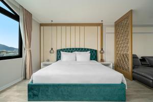 a bedroom with a large white bed and a couch at Lupin Center Da Nang Hotel in Danang