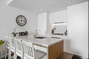 a white kitchen with a counter and a clock on the wall at Chic 1-Bed with Parking, Rooftop Pool and Gym in Brisbane