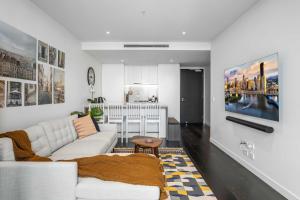 a living room with a white couch and a kitchen at Chic 1-Bed with Parking, Rooftop Pool and Gym in Brisbane