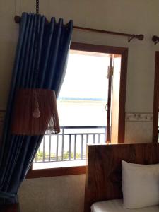 a room with a window with a blue curtain at Le Tonle in Kratie