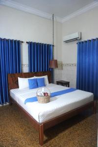 a bed with blue curtains and a basket on it at Le Tonle in Kratie