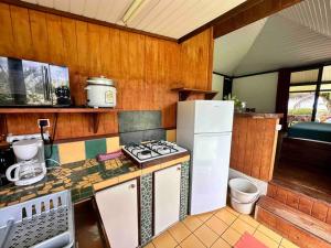 uma cozinha com um fogão e um frigorífico branco em Fare Mahana - plage priveé avec vue sur Tahiti em Maatea