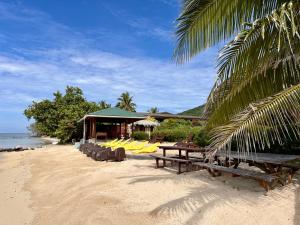 uma praia com mesas e cadeiras e um edifício em Fare Mahana - plage priveé avec vue sur Tahiti em Maatea