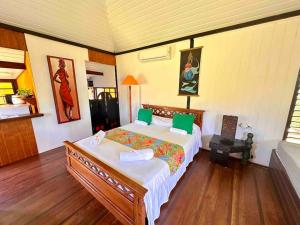 una camera da letto con un letto grande con cuscini verdi di Fare Mahana - plage priveé avec vue sur Tahiti a Maatea