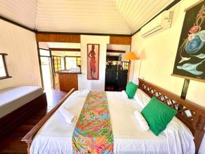 um quarto com 2 camas e almofadas verdes em Fare Mahana - plage priveé avec vue sur Tahiti em Maatea