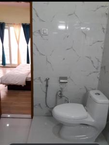 a white bathroom with a toilet and a bedroom at Joshi Holiday Home Stay in Lansdowne