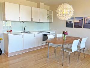 uma cozinha com uma mesa de madeira e armários brancos em 4 person holiday home in Gudhjem em Gudhjem