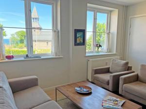 uma sala de estar com uma mesa, cadeiras e janelas em 4 person holiday home in Gudhjem em Gudhjem