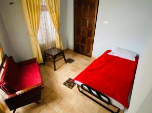 um quarto com uma cama vermelha e uma cadeira em BOB Leisure em Ooty