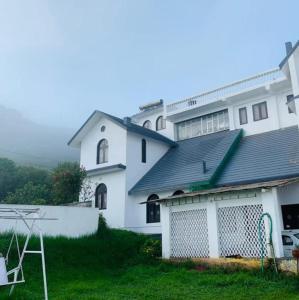 una grande casa bianca con un garage nel cortile di BOB Leisure a Ooty