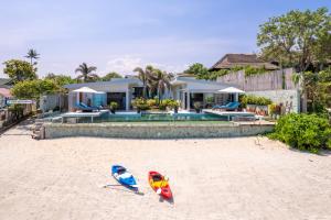 two kayaks on the beach in front of a house at Villa Playa Samui in Choeng Mon Beach