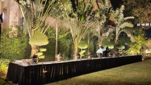 una mesa larga en un jardín con palmeras en KASHI ANANDAM SPIRITUAL & WELLNESS VEDIC VILLAGE LLP en Kakarmatha