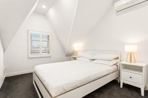 een witte slaapkamer met een wit bed en een raam bij Chic 3-Bed House with a Cosy Courtyard in Sydney