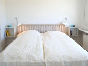 a bed with two white blankets and two shelves at 4 person holiday home in Svaneke in Svaneke