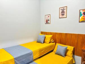 1 dormitorio con 2 camas con sábanas amarillas en NgeKost harian, en Alastuwo